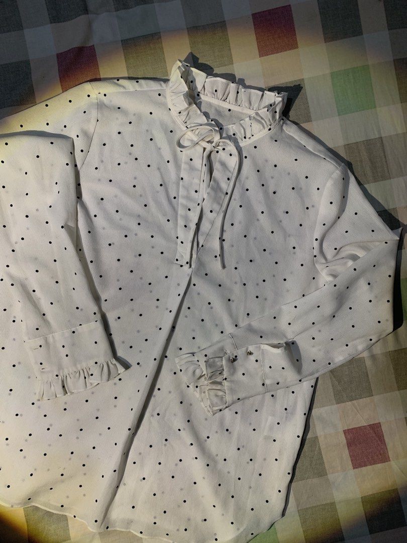 White Polka Dot Long Sleeve Blouse with Ruffles (Category: Blouses) located in Rizal. Submitted by pcesspscl145 (Listing ID 1469707521, Image 2). Description: - Color/Pattern: White with all-over black polka dots - Design: High ruffled collar with front tie closure - Sleeves: Long sleeves with buttoned cuffs and ruffled wrist details - Fabric: Lightweight with a subtle vertical ribbed texture - Fit: Curved hemline, easy to style for office or cas