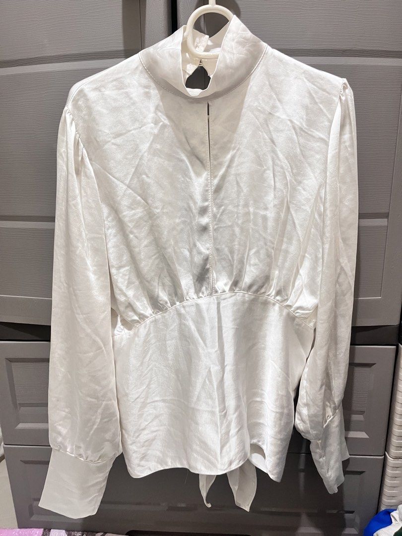 White Satin Tie-Back Long Sleeve Blouse (Category: Blouses) located in Taguig. Submitted by notyoursam (Listing ID 1469689909, Image 1). Description: - Color: White - Material: Silky satin with a subtle sheen - Design: Long sleeves with buttoned cuffs, high neckline with back button closure - Feature: Trendy open-back design with a self-tie knot detail at the hem - Styling: Perfect to pair with high-waisted trousers or skirts for work or dinner d
