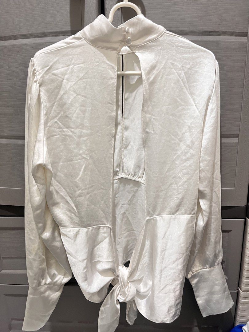 White Satin Tie-Back Long Sleeve Blouse (Category: Blouses) located in Taguig. Submitted by notyoursam (Listing ID 1469689909, Image 2). Description: - Color: White - Material: Silky satin with a subtle sheen - Design: Long sleeves with buttoned cuffs, high neckline with back button closure - Feature: Trendy open-back design with a self-tie knot detail at the hem - Styling: Perfect to pair with high-waisted trousers or skirts for work or dinner d