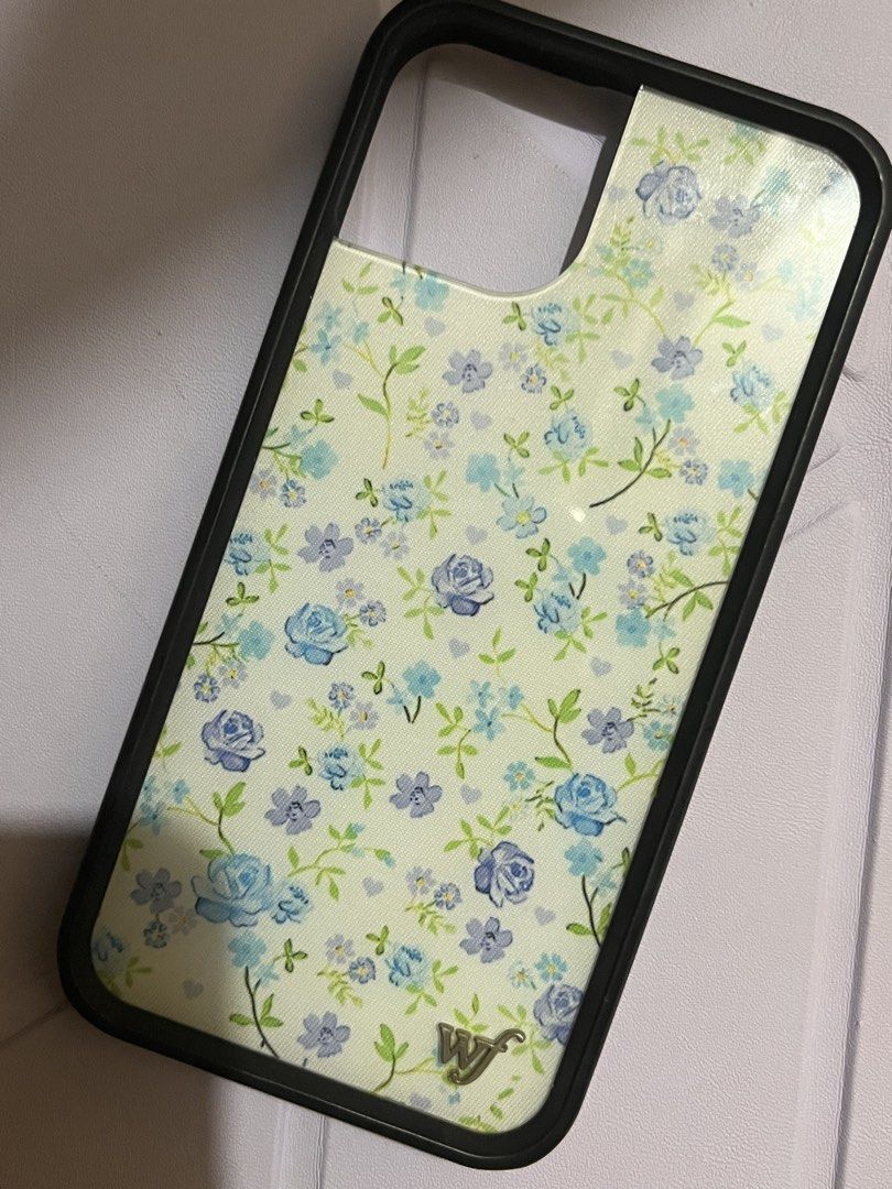Wildflower Case for Iphone 13/14 (Category: Cases & Sleeves) located in Legazpi City. Submitted by sandras. (Listing ID 1469701629, Image 2). Description: - Brand: Wildflower Cases - Compatibility: Designed for iPhone 13 and iPhone 14 - Design: Aesthetic blue floral print with green vines and tiny heart details - Features: Durable black protective bumper frame and signature metal 'WF' logo - Condition: Excellent, well-maintained.