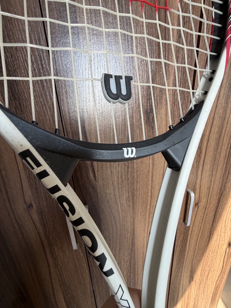 Wilson Fusion Tennis Racket (Category: Racket and Ball Sports) located in Quezon City. Submitted by mdjheavyequipment (Listing ID 1469639192, Image 2). Description: - Brand/Model: Wilson Fusion tennis racket - Design: Sleek white and black frame with the classic red Wilson logo - Extras: Includes a vibration dampener and a white overwrap on the handle (minor wear from previous play) - Condition: Standard strung setup, ready to use on the court.