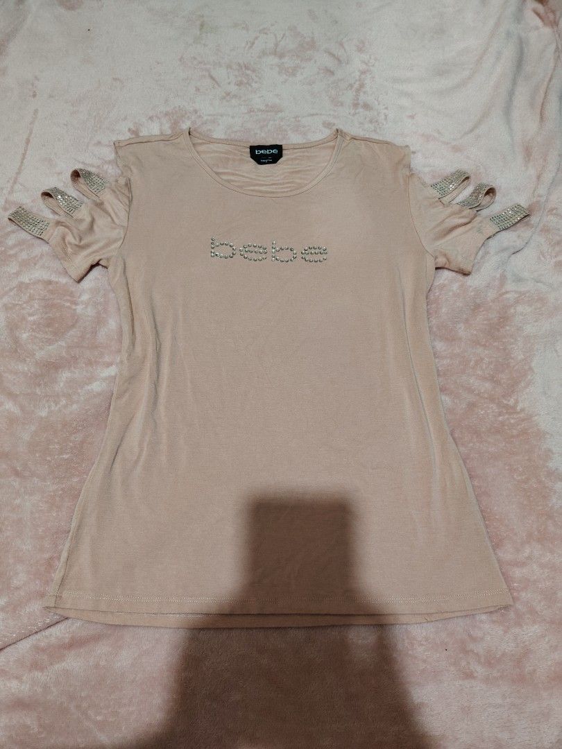 Y2k Bebe Rhinestone Cold Shoulder Top Size M (Category: Sleeveless) located in Villasis. Submitted by trip_thrift15 (Listing ID 1469702656, Image 1). Description: - Brand: Bebe - Color: Pink - Size: Medium - Material: Soft cotton blend - Design: Cold shoulder with rhinestone-accented straps - Detail: Signature Bebe rhinestone logo spelled out on the chest - Neckline: Classic round neckline - Condition: Excellent pre-loved or brand new (ready to w