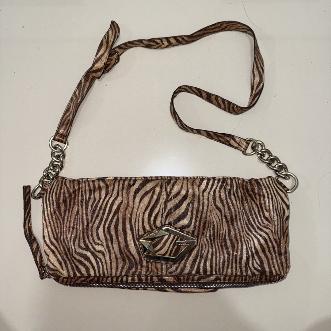 Y2k Guess zebra-print shoulder bag (Category: Shoulder Bags) located in Calasiao. Submitted by jafaith_man (Listing ID 1469708323, Image 1). Description: Y2K GUESS brown and tan zebra-print shoulder bag featuring a geometric gold-tone center logo plaque, a zipper accent along the bottom, and a chain-and-fabric convertible strap..