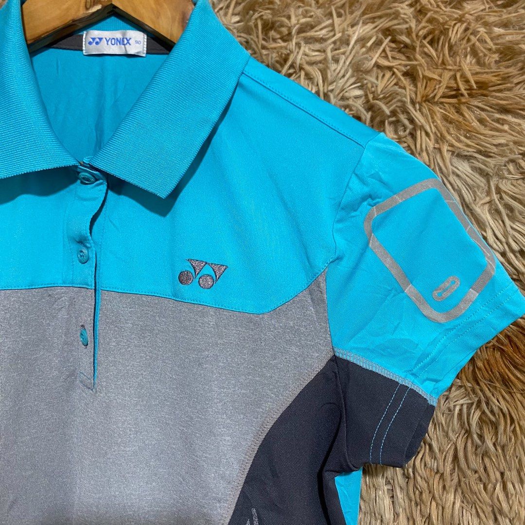 Yonex Blue Grey Athletic Polo Shirt (Category: Activewear) located in Butuan. Submitted by jc13thrifts (Listing ID 1469752504, Image 2). Description: - Brand: Yonex - Colorway: Blue, grey, and dark charcoal - Size: 90 (Inner collar tag) - Design: Short sleeves with silver graphic outline, classic collar, and 3-button placket with branded buttons - Detailing: Embroidered Yonex logo on the chest - Material: Lightweight fabric - Ideal for: Badminton