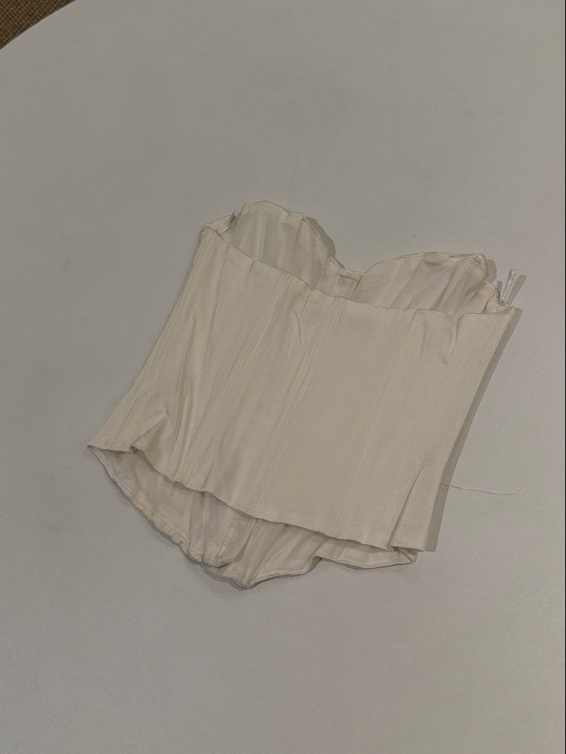 Zara White Corset Top Size M (Category: Sleeveless) located in Muntinlupa City. Submitted by henlo03 (Listing ID 1469613523, Image 3). Description: - Brand/Model: Zara White Corset Top - Size: M (Made in Turkey) - Design: Sweetheart neckline, subtle front ruching texture, and center front hook-and-eye closure - Structure: Built-in boning throughout for shape and support - Condition: Great overall, with minor yellowing near the bottom hem (visible