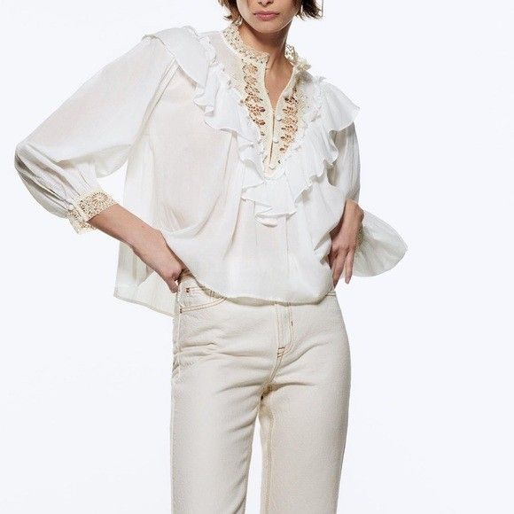 ZARA White Lace Ruffle Blouse Top (Category: Blouses) located in Taguig. Submitted by ashie_clothing (Listing ID 1469687028, Image 1). Description: - Brand: Zara - Color: White with beige lace accents - Condition: Brand new with tag attached - Features: Ruffle trim front, high neckline with crochet lace edging - Sleeves: Long sleeves with matching lace cuffs - Closure: Covered button placket.