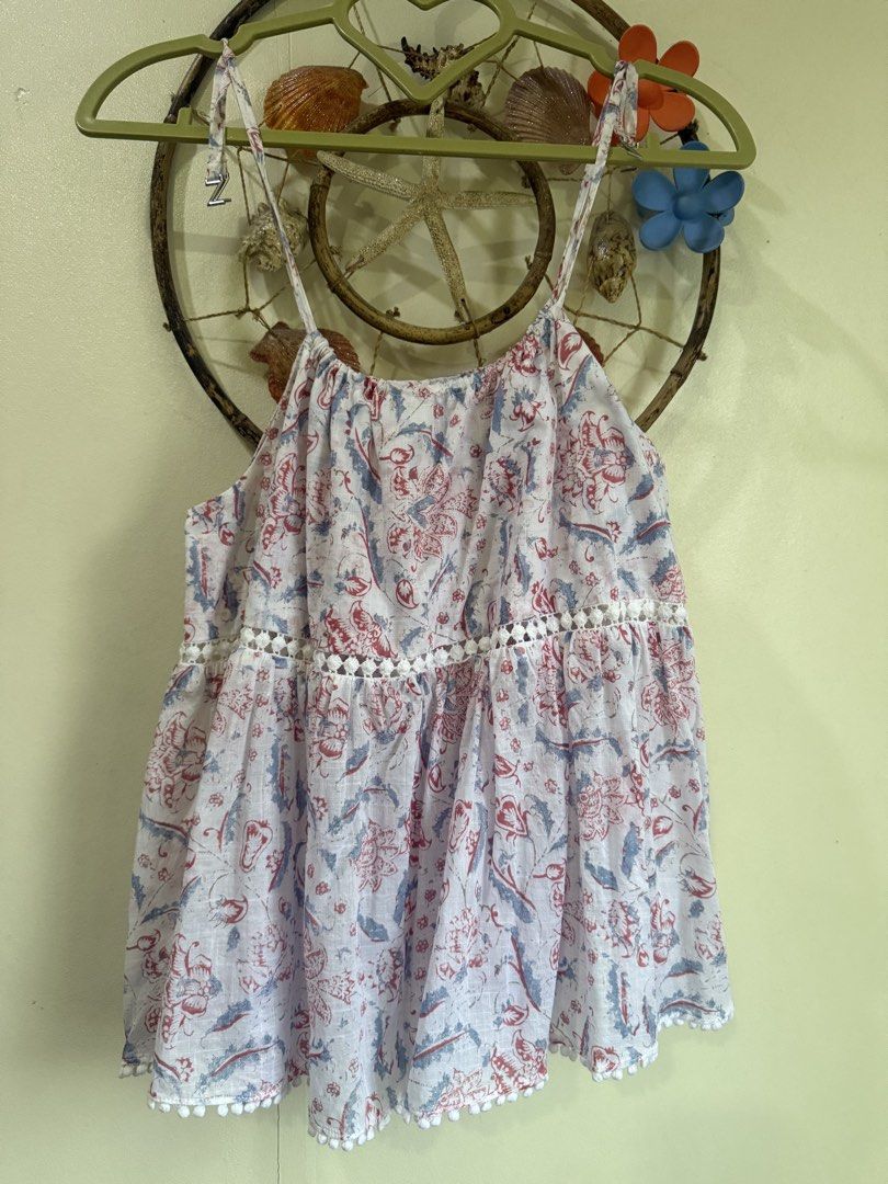 Zimmermann cotton printed tank top size 0 (Category: Sleeveless) located in Cebu City. Submitted by hotchkisscebu (Listing ID 1469643394, Image 1). Description: - Brand: Zimmermann - Material: 100% lightweight and breezy cotton - Design: White base with a vibrant red and blue floral print - Details: Delicate spaghetti straps with hardware adjusters, chic cutout lace trim around the midsection, and playful pom-pom trim along the bottom hem - Size: