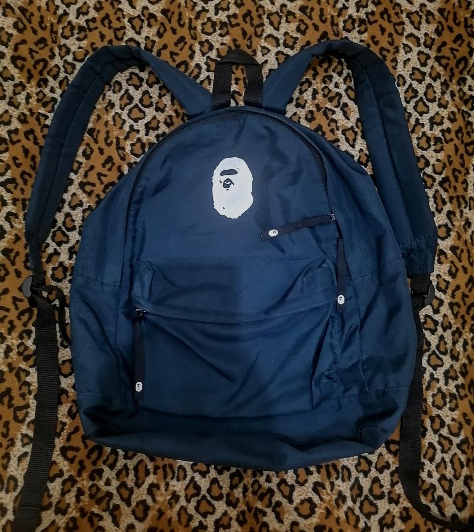 A Bathing Ape BAPE Navy Blue Backpack (Category: Backpacks) located in Cebu City. Submitted by roadthrift (Listing ID 1469937796, Image 1). Description: - Authentic dark blue BAPE backpack with large white ape head logo - Features a secure main compartment and convenient front zipped pocket - Comfortable, adjustable black shoulder straps for daily use - Crafted from durable 100% polyester (A Bathing Ape Nowhere Co., Made in China) - Condition: Ex