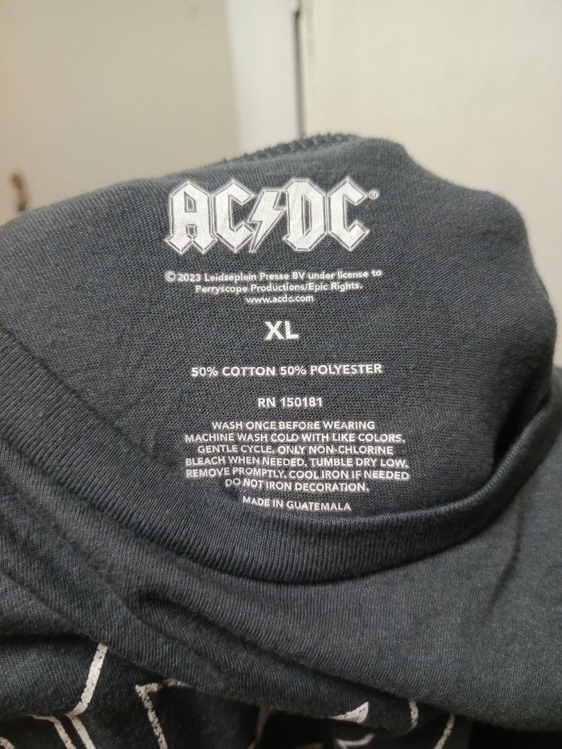 AC/DC Graphic Tee Dark Grey XL (Category: Tshirts & Polo Shirts ) located in Cabatuan. Submitted by penthegreat (Listing ID 1469781688, Image 3). Description: 21 or 22 width & 26 length - Band: Official AC/DC merchandise (2023) - Color: Dark grey with a plain back - Design: Stacked logo with colorful lightning bolts on the front - Size: XL (tag printed inside the collar) - Material: 50% cotton, 50% polyester blend - Origin: Made in Guatemala.