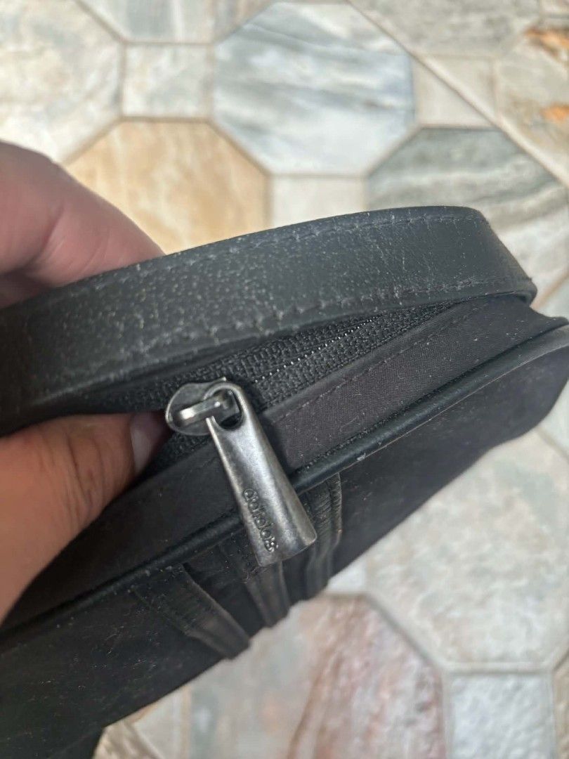 Adidas Black Shoulder Bag (Category: Sling Bags) located in Caloocan City. Submitted by joshuadyogi0122 (Listing ID 1469810791, Image 3). Description: - Brand: Adidas - Color: Classic black with light grey interior lining - Design: Iconic three stripes on front with metal Adidas logo plate - Closure: Secure zip closure with branded metal puller - Compartments: Handy inner slip pocket for organization - Details: Production date 05/06, Article No. 