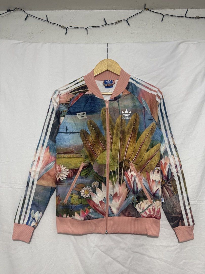 Adidas Floral Track Jacket Bomber (Category: Coats, Jackets and Outerwear) located in Quezon City. Submitted by dapanaaaay (Listing ID 1469861639, Image 1). Description: - Brand: Adidas - Style: Zip-up track jacket with a vibrant botanical and water lily print - Details: Pink ribbed collar, cuffs, and hem, iconic white three stripes on sleeves, and white trefoil logo on the chest - Features: Convenient side pockets with zippers - Measurements: 18