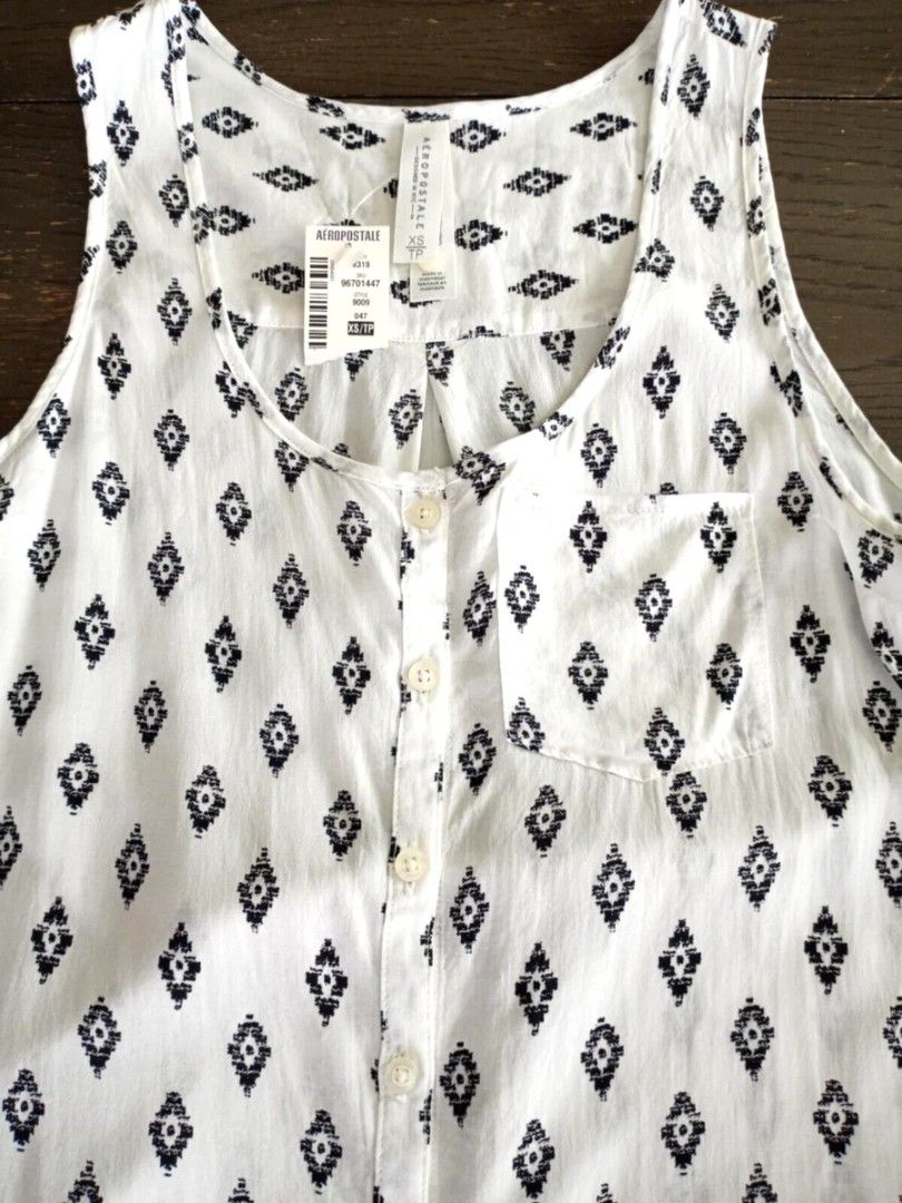Aeropostale White Black Pattern Tank Top Size XS (Category: Sleeveless) located in Paranaque City. Submitted by calm_youngstore7 (Listing ID 1469772440, Image 3). Description: - Brand: Aeropostale - Condition: Brand new with original store tags - Size: XS - Color: White with black geometric diamond print - Features: Button-down front, chest pocket, and rounded high-low hem - Origin: Made in Indonesia.