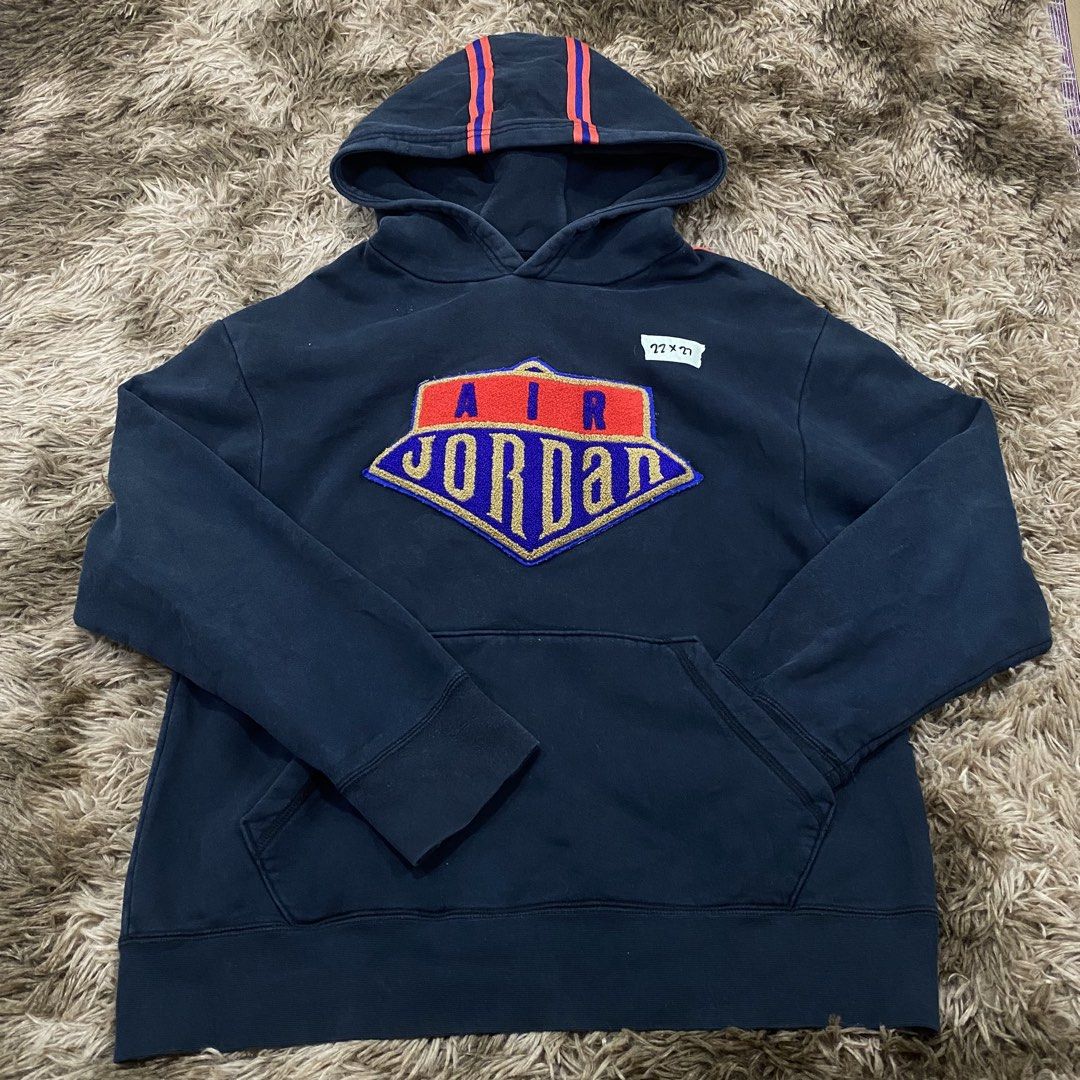 Air Jordan Navy Blue Pullover Hoodie Size L (Category: Coats, Jackets and Outerwear) located in Cagayan de Oro. Submitted by sepamorash53558 (Listing ID 1469795732, Image 1). Description: - Brand: Air Jordan - Color: Navy blue with red accents - Size: Large (Flat lay: 22" pit-to-pit, 27" length) - Material: 82% cotton, 18% polyester - Design: Large embroidered shield logo on chest - Features: Drawstring hood with red stripes, front kangaroo pocke