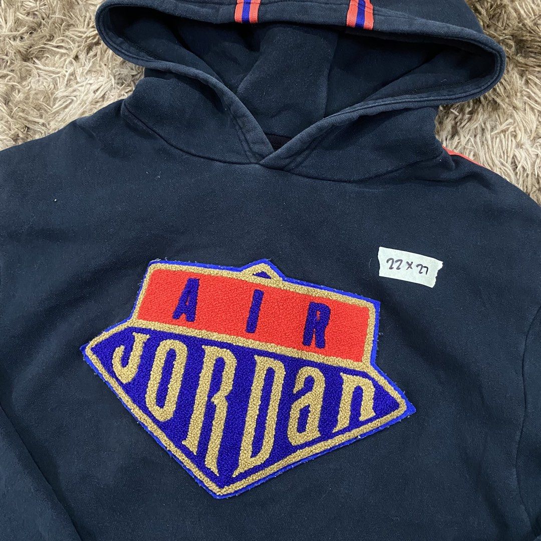 Air Jordan Navy Blue Pullover Hoodie Size L (Category: Coats, Jackets and Outerwear) located in Cagayan de Oro. Submitted by sepamorash53558 (Listing ID 1469795732, Image 2). Description: - Brand: Air Jordan - Color: Navy blue with red accents - Size: Large (Flat lay: 22" pit-to-pit, 27" length) - Material: 82% cotton, 18% polyester - Design: Large embroidered shield logo on chest - Features: Drawstring hood with red stripes, front kangaroo pocke