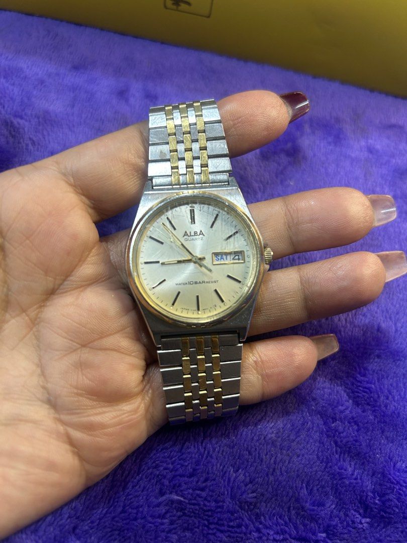 Alba Quartz Two-Tone Men's Watch (Category: Men's Watches) located in Cavite. Submitted by mamamia73 (Listing ID 1469902475, Image 2). Description: Alba quartz watch with a two-tone silver and gold bracelet. Cream dial featuring day and date display at the three o'clock position. Water resistant up to ten bars. Signed clasp with Alba branding. Shows scratches on the crystal and minor wear on the case and band. Standard deployment clasp closure..
