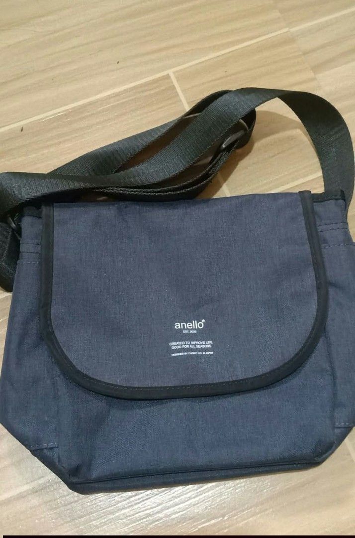 Anello dark blue messenger bag (Category: Sling Bags) located in Gapan. Submitted by montesnora80204 (Listing ID 1469785230, Image 1). Description: - Brand: Anello - Color: Dark blue - Strap: Adjustable black shoulder strap - Closure: Front flap closure with white logo print - Hardware: Includes attached Anello carabiner clip - Compartments: Main compartment with inside zip pocket, plus a back slip pocket - Condition: Clean fabric exterior and in