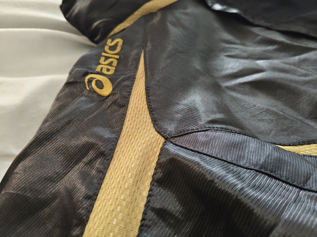 Asics Black And Gold Windbreaker Jacket (Category: Coats, Jackets and Outerwear) located in Manila. Submitted by ian.frias_ (Listing ID 1469841388, Image 2). Description: Asics windbreaker in black with gold stripe accents. Lightweight material with ribbed cuffs and full zip front. Classic sports jacket design from Asics. Great piece for runs or casual wear..