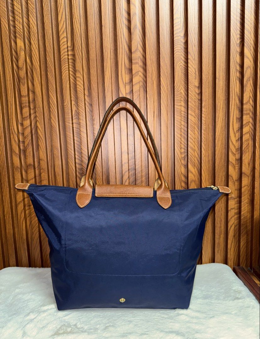 Authentic Longchamp Le Pliage Nylon Tote Bag Navy Blue (Category: Everything Else Others) located in Subic. Submitted by luxshoppe88 (Listing ID 1469863401, Image 2). Description: - Authentic Longchamp Le Pliage shoulder tote bag in classic navy blue - Brown leather handles and flap with secure gold-tone snap closure - Spacious main compartment featuring a convenient small interior pocket - Lightweight, foldable design ideal for daily commutes, w