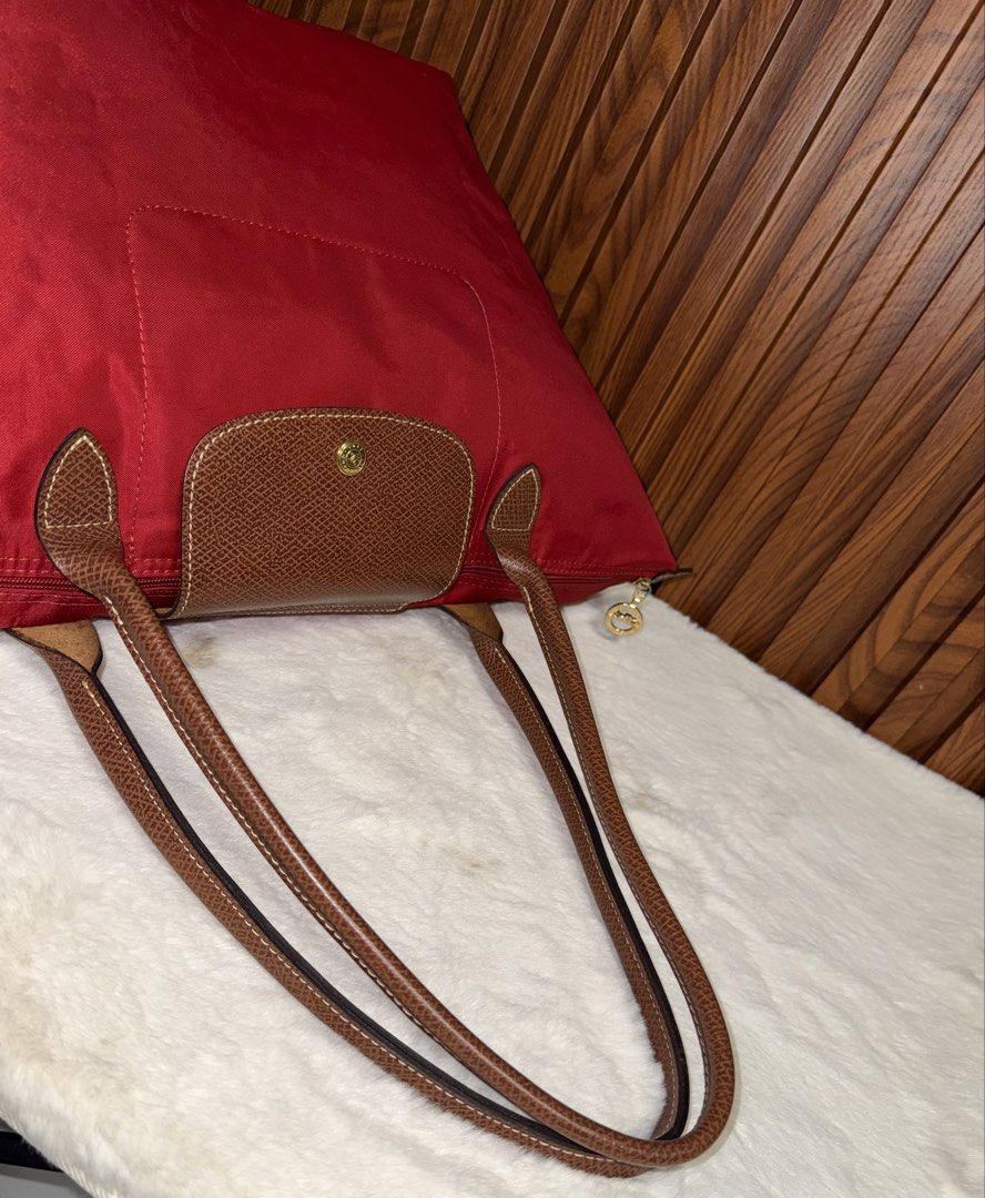 Authentic Longchamp Le Pliage Red Tote Bag (Category: Everything Else Others) located in Subic. Submitted by luxshoppe88 (Listing ID 1469864191, Image 3). Description: - Brand: Authentic Longchamp Le Pliage Red Tote Bag - Color: Vibrant red nylon with brown leather trim - Hardware: Gold-tone hardware with secure zip top and snap flap - Interior: Spacious main compartment with convenient slip pocket - Design: Lightweight, foldable, and versatile f