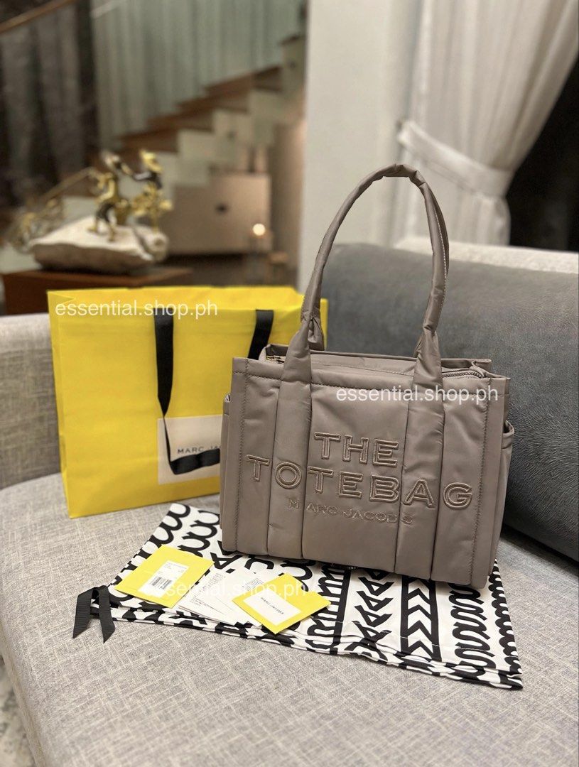 Authentic Marc Jacobs Medium Puffer Tote Cement (Category: Tote Bags) located in Manila. Submitted by essential.shop.ph (Listing ID 1469930683, Image 1). Description: FOR PRE-ORDER. 7-10 days ETA ☺️ Authentic Marc Jacobs Nylon Medium Puffer Tote Cement color Top zip closure Top handle 2 external side pockets 1 Interior Slip Pocket, 1 Interior Zip Pocket Polyester Lining Includes paper bag, dust bag, tag and care cards. Dimensions L 33cm x D 15cm 