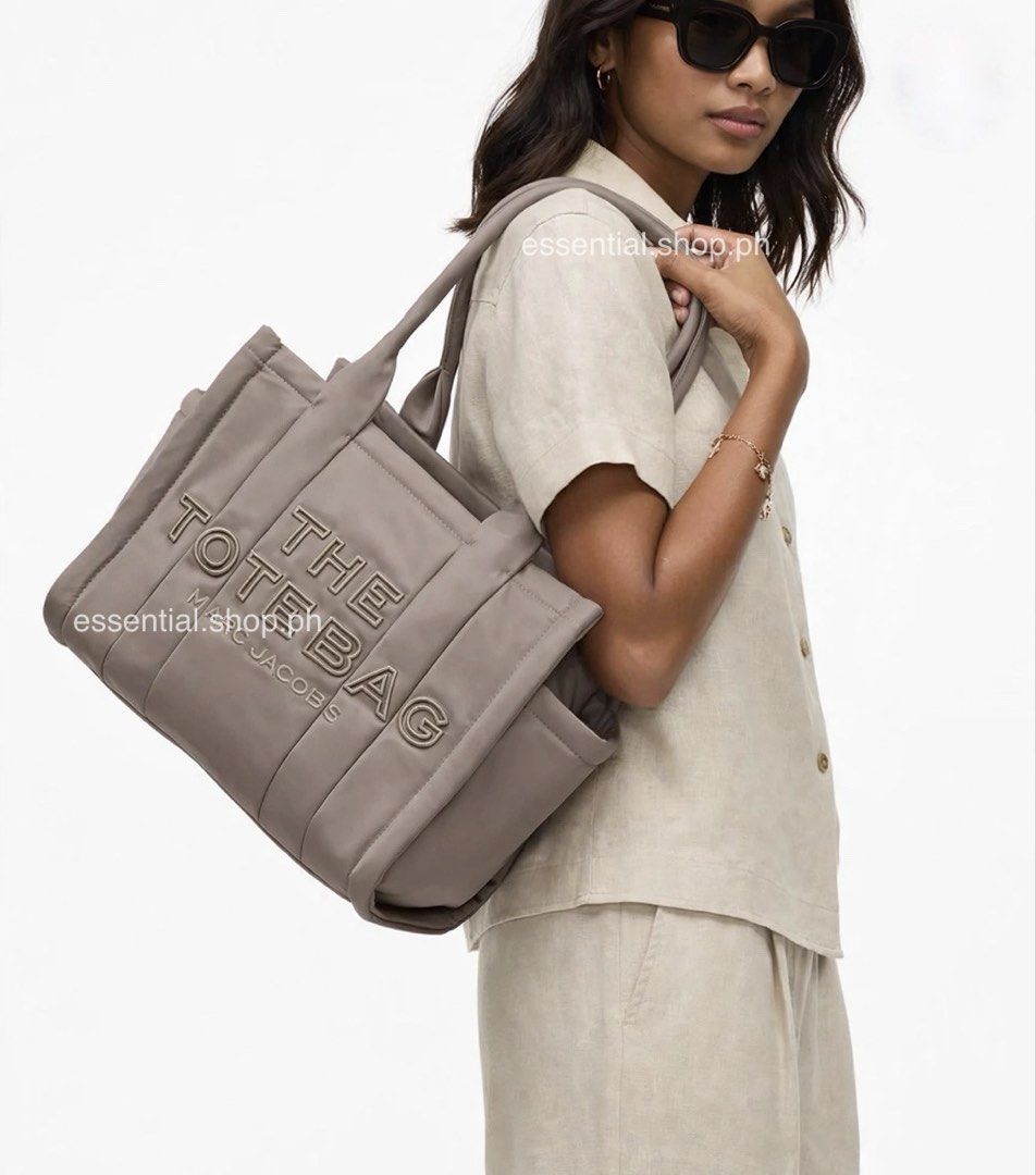 Authentic Marc Jacobs Medium Puffer Tote Cement (Category: Tote Bags) located in Manila. Submitted by essential.shop.ph (Listing ID 1469930683, Image 2). Description: FOR PRE-ORDER. 7-10 days ETA ☺️ Authentic Marc Jacobs Nylon Medium Puffer Tote Cement color Top zip closure Top handle 2 external side pockets 1 Interior Slip Pocket, 1 Interior Zip Pocket Polyester Lining Includes paper bag, dust bag, tag and care cards. Dimensions L 33cm x D 15cm 