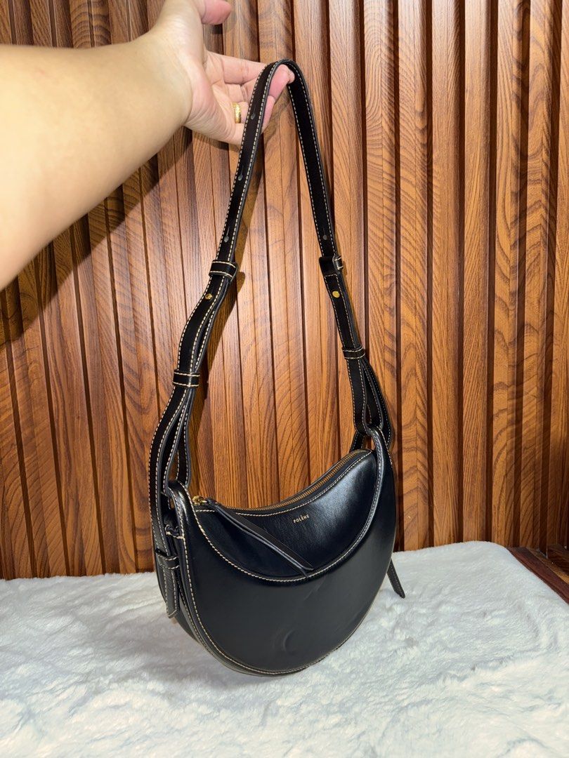 Authentic Polène Black Leather Shoulder Bag (Category: Everything Else Others) located in Subic. Submitted by luxshoppe88 (Listing ID 1469857473, Image 2). Description: Polène black leather shoulder bag with contrast stitching. Curved crescent shape with gold-tone hardware and top zip closure. Adjustable strap with multiple settings. Interior has a clean fabric lining with a slip pocket. Minimalist design goes with everything. Shows minor wear on