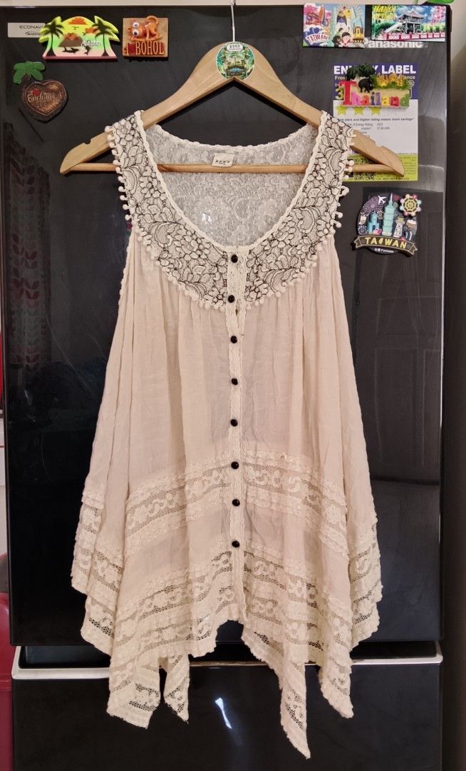 axes femme Lace Collar Button Down Blouse (Category: Blouses) located in Manila. Submitted by keencrystal.595c28 (Listing ID 1469833841, Image 1). Description: Cream sleeveless top from axes femme. Detailed with black floral lace around the neckline, pom-pom trim, and front buttons. Layered lace panels near the hem create an asymmetrical, flowy look. Size tag shows M. Lightweight, breezy material. Great piece for layering or warm weather..