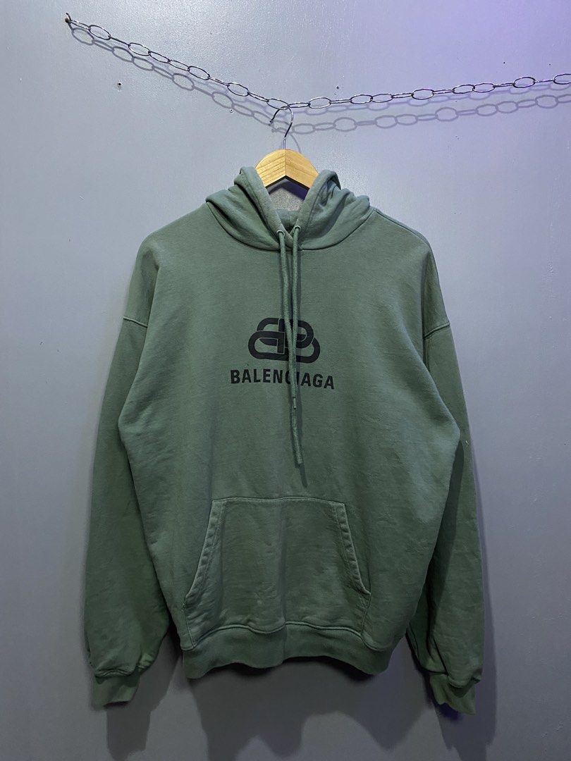 Balenciaga BB Mode Green Hoodie (Category: Hoodies) located in Caloocan City. Submitted by retrowear.gallery (Listing ID 1469777345, Image 1). Description: - Brand: Balenciaga - Color: Muted sage green - Design: Large BB logo graphic printed on the chest - Features: Drawstring hood, front kangaroo pocket, ribbed cuffs and hem - Origin: Made in Portugal - Condition/Details: Collar tag and interior wash labels attached - Perfect for elevated street