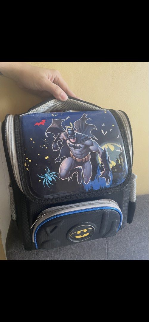 Batman Kids School Backpack with Hard Shell Front (Category: Babies & Kids Fashion) located in Manila. Submitted by zealturtle_0fa233 (Listing ID 1469925449, Image 1). Description: Batman school backpack for young fans. Hard shell front pocket with classic yellow bat logo and graphic action scene on the top flap. Black and grey color scheme with mesh side pockets for water bottles. Padded adjustable shoulder straps and top carry handle. Mesh padd