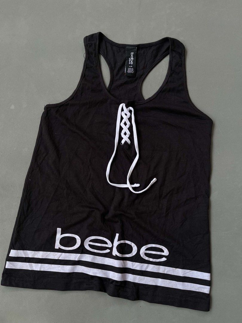 bebe Black Lace-Up Tank Top (Category: Sleeveless) located in Baguio. Submitted by lovelaira (Listing ID 1469852504, Image 2). Description: Black bebe racerback tank top in size L. White lace-up drawstring front with metal grommets. White bebe branding and double stripe detail near the bottom hem. Material is 58% cotton, 37% polyester, 5% spandex. Soft and stretchy sleepwear fabric. Clean tag intact..