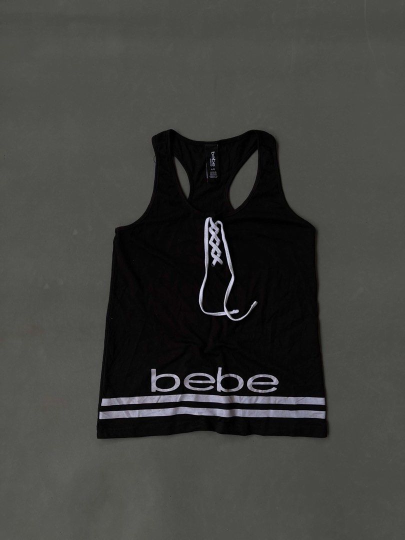 bebe Black Lace-Up Tank Top (Category: Sleeveless) located in Baguio. Submitted by lovelaira (Listing ID 1469852504, Image 1). Description: Black bebe racerback tank top in size L. White lace-up drawstring front with metal grommets. White bebe branding and double stripe detail near the bottom hem. Material is 58% cotton, 37% polyester, 5% spandex. Soft and stretchy sleepwear fabric. Clean tag intact..