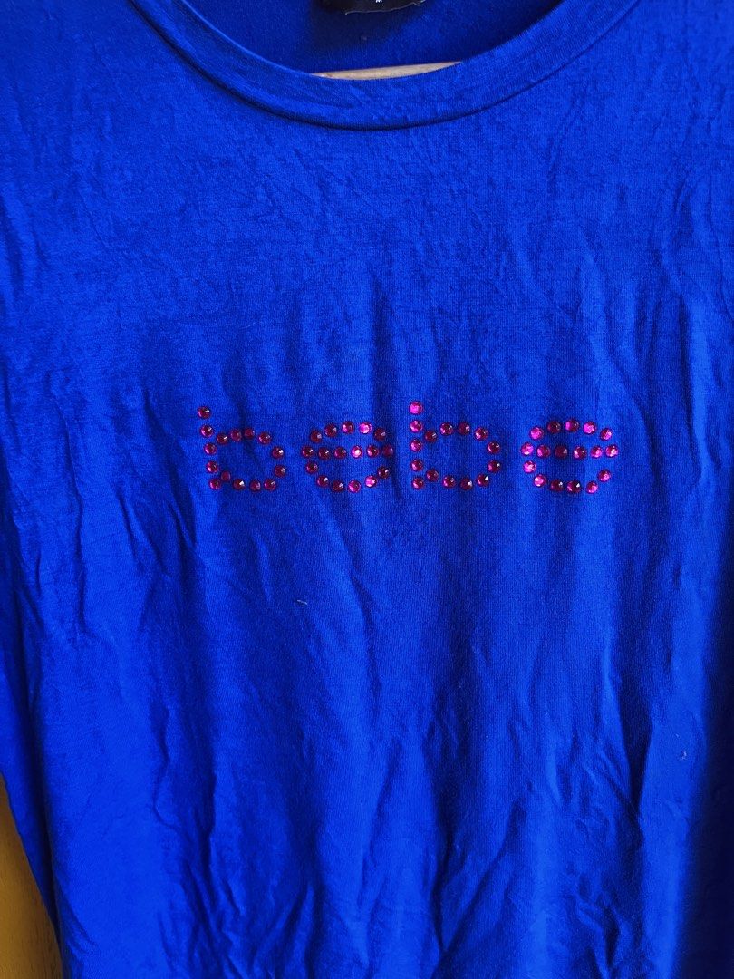 bebe Blue T-shirt with Rhinestone Logo (Category: Shirts) located in Manila. Submitted by seth_inting. (Listing ID 1469910227, Image 3). Description: - Brand: bebe - Color: Bright blue - Size: M - Material: Soft cotton blend - Details: Pink rhinestone logo embellishment on chest, crew neck, standard fit - Condition: Great for casual everyday wear - Origin: Made in China.