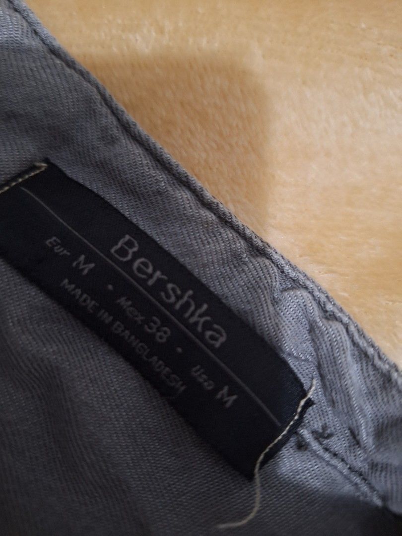 Bershka Grey Sleeveless Button-Up Top Size M (Category: Sleeveless) located in Paranaque City. Submitted by ellech16 (Listing ID 1469832747, Image 2). Description: - Brand: Bershka - Size: M (Mex 38, USA M) - Color: Grey - Material: Lightweight denim-style fabric - Features: Dual chest pockets, button placket, curved high-low hem - Condition: Excellent, pre-loved - Style: Casual and easy to pair with jeans or shorts.