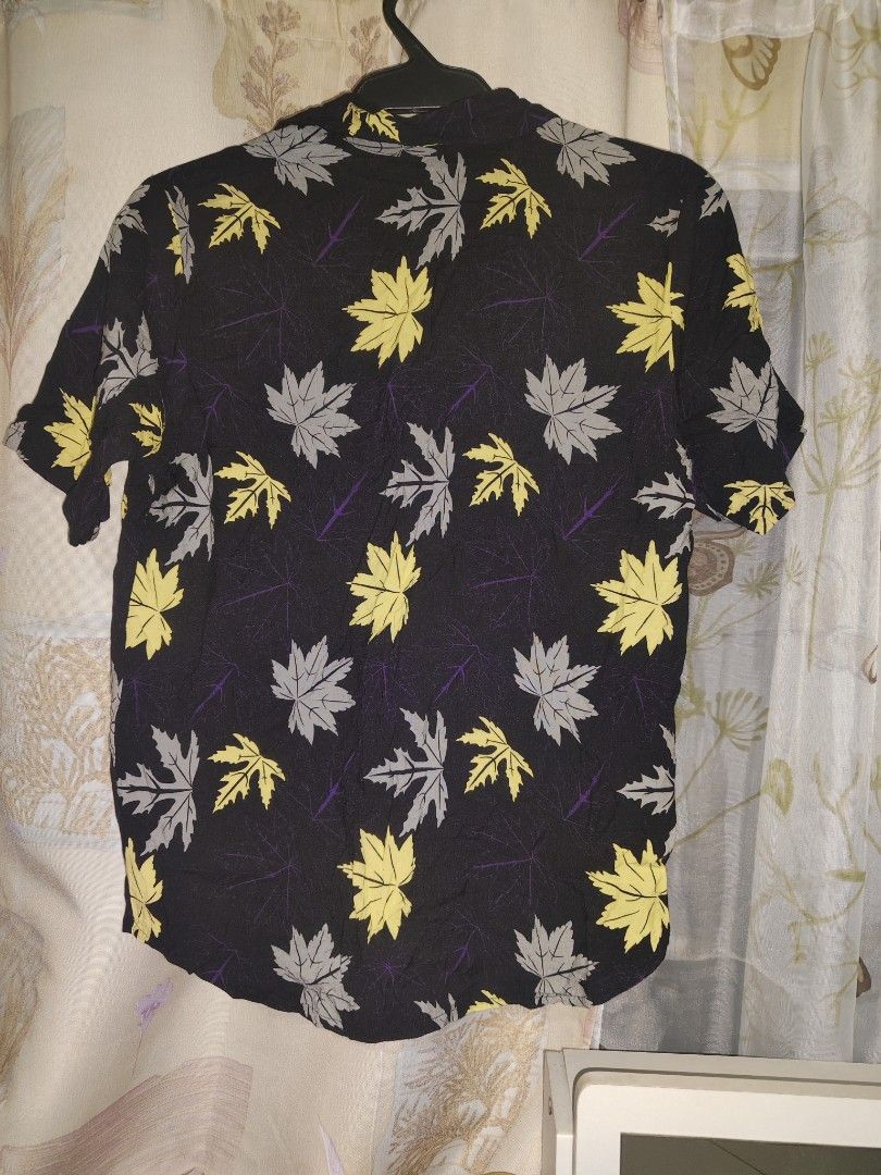 Black Leaf Print Short Sleeve Button-Up Shirt (Category: Babies & Kids Fashion) located in Manila. Submitted by duffy-080 (Listing ID 1469897377, Image 2). Description: - Style: Short sleeve button-up with classic camp collar - Pattern: Vibrant yellow and grey maple leaf print on black - Fabric: Lightweight and breathable for warm weather - Closure: Front button-up - Size: Tagged 2XL - Condition: Clean overall, great ready-to-wear condition -use 