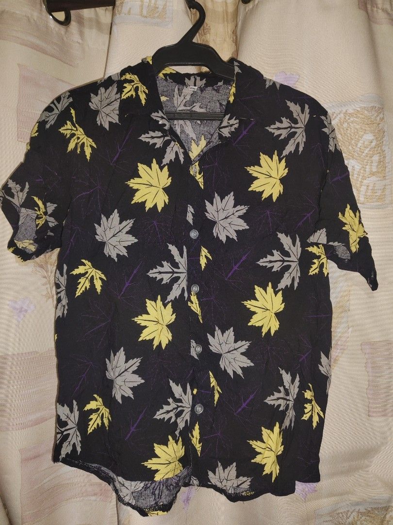 Black Leaf Print Short Sleeve Button-Up Shirt (Category: Babies & Kids Fashion) located in Manila. Submitted by duffy-080 (Listing ID 1469897377, Image 1). Description: - Style: Short sleeve button-up with classic camp collar - Pattern: Vibrant yellow and grey maple leaf print on black - Fabric: Lightweight and breathable for warm weather - Closure: Front button-up - Size: Tagged 2XL - Condition: Clean overall, great ready-to-wear condition -use 