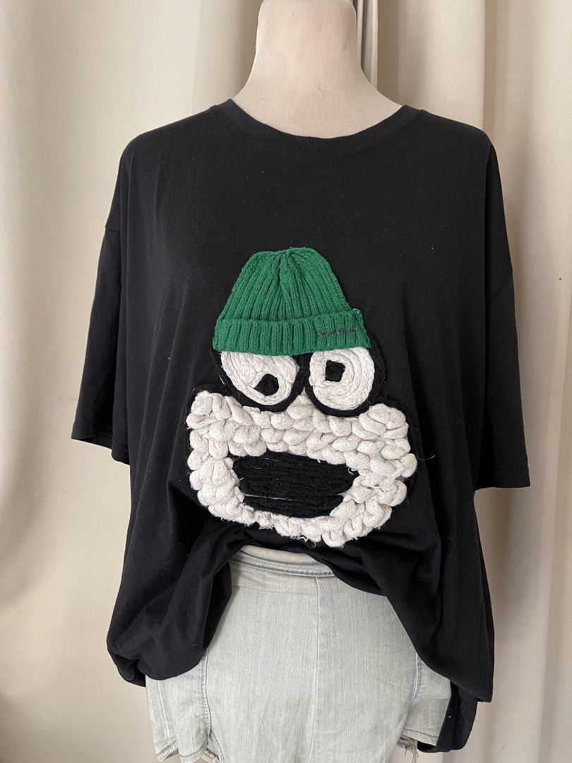 Black TEE with 3D Textured Cartoon (Category: Shirts) located in Cainta. Submitted by zlove111 (Listing ID 1469769809, Image 2). Description: Black t-shirt featuring a funny cartoon character appliqué on the front. Includes a knitted green beanie, big swirling eyes, textured white beard, and black mouth detail. Short sleeves, crew neckline, relaxed fit. Made from comfortable cotton material. Fun streetwear piece. cotton oversize up to xxl 24" .