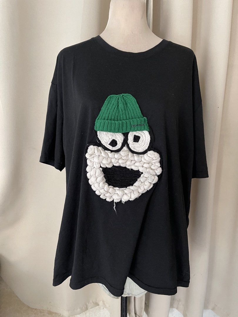 Black TEE with 3D Textured Cartoon (Category: Shirts) located in Cainta. Submitted by zlove111 (Listing ID 1469769809, Image 1). Description: Black t-shirt featuring a funny cartoon character appliqué on the front. Includes a knitted green beanie, big swirling eyes, textured white beard, and black mouth detail. Short sleeves, crew neckline, relaxed fit. Made from comfortable cotton material. Fun streetwear piece. cotton oversize up to xxl 24" .