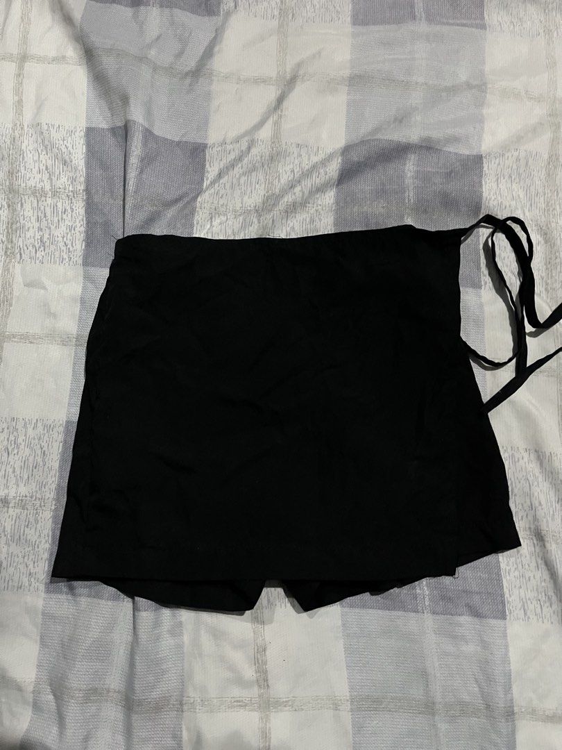 Black wrap skort with side tie (Category: Skirts) located in Legazpi City. Submitted by chynnunez (Listing ID 1469878557, Image 1). Description: - Color: Classic Black - Style: Wrap-style skort with a chic front flap design - Closure: Adjustable side tie with matching fabric straps - Comfort: Built-in shorts underneath for worry-free wear - Versatility: Easy to pair with basic tops, perfect for everyday casual outfits.