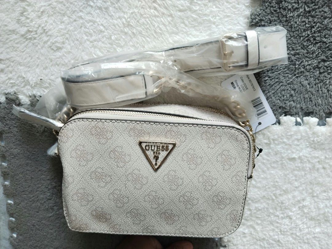 [BNWT] GUESS Noelle Camera Crossbody Bag (Category: Luxury Bags & Wallets) located in Valenzuela. Submitted by wiskyyyyy (Listing ID 1469865807, Image 2). Description: Condition: Brand New with Tags & protective plastic intact 📍 Style Code: BD787913 (Guaranteed Authentic) Product Details: Color: Dove Logo (Off-White / Beige print with gold hardware) Material: Premium PU leather with iconic GUESS 4G monogram Zip closure with adjustable chain-acce