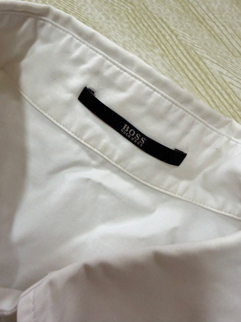 BOSS Hugo Boss White Button Up Shirt (Category: Tshirts & Polo Shirts ) located in Quezon City. Submitted by marifavo (Listing ID 1469820583, Image 2). Description: - Brand: BOSS Hugo Boss - Color: Solid white - Style: Classic button-up shirt with standard collar - Details: Clean neckline featuring the signature black brand tag inside the collar - Versatility: Ideal for work, business, or formal events - Condition: Clean and ready to wear.