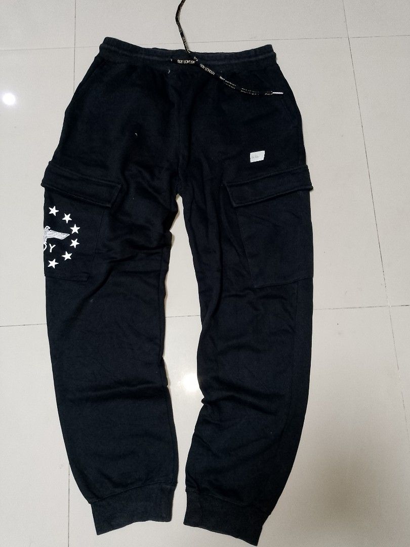 Boy London Black Cargo Sweatpants Joggers (Category: Joggers) located in Manila. Submitted by mjthrifted_second (Listing ID 1469833704, Image 1). Description: Code 10 - Brand: Boy London (Authentic) - Color: Black - Style: Sweatpants with cargo pockets, drawstring waist, and elastic cuffs - Details: Eagle logo and stars graphic on the right leg - Back Print: 'LEAVE THE BOY ALONE' text on the back leg - Condition: Branded drawstrings and interior 