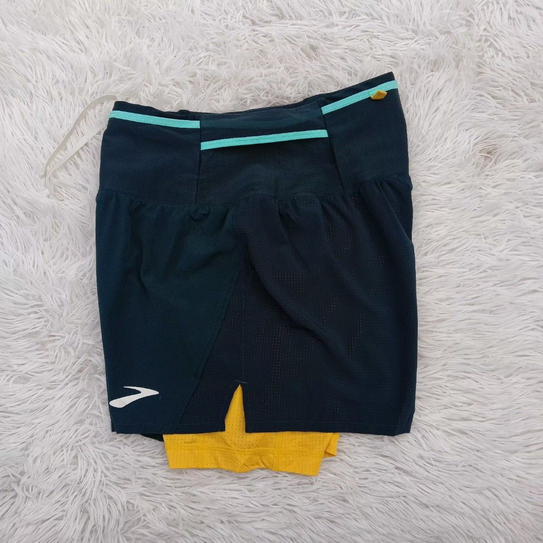 Brooks Trail Running Shorts Size S (Category: Shorts) located in Gattaran. Submitted by thrift_wiseph (Listing ID 1469854403, Image 1). Description: - Brand: Brooks - Item: Trail Running Shorts - Color: Dark blue with yellow inner lining and teal trim - Size: S - Material: Lightweight perforated fabric for outdoor runs - Storage: Built-in waistband pockets - Design: Trail coordinate graphics printed on the back - Origin: Made in Vietnam.