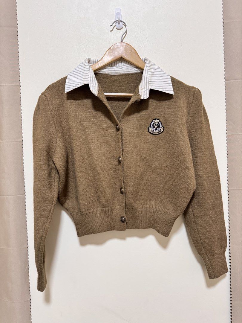 Brown Collared Cardigan with Crest Patch (Category: Coats, Jackets and Outerwear) located in Manila. Submitted by seayouncey (Listing ID 1469929498, Image 1). Description: - Style: Preppy academic vibe, easy to throw on over basic tees - Design: Button-up front with ornate buttons and embroidered crest patch on the chest - Details: Attached striped shirt collar, long sleeves with puffed shoulders - Fit: Cropped length with ribbed hem and cuffs - 