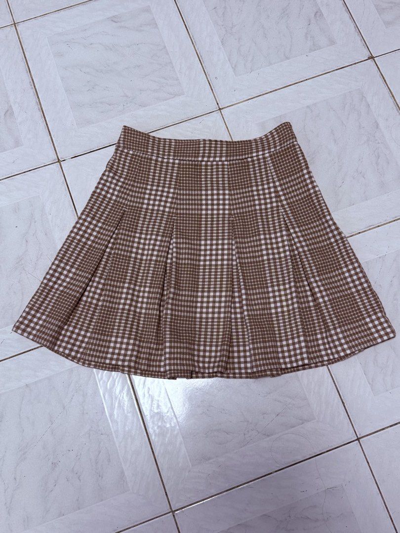 Brown Plaid Pleated Skirt (Category: Skirts) located in Agdangan. Submitted by onahhhh (Listing ID 1469774506, Image 1). Description: - Style: Brown and white checkered pleated skirt - Design: Classic plaid pattern with all-over box pleats - Fit: Structured waistband for a clean look - Closure: Convenient side zipper - Perfect for: Autumn outfits paired with sweaters or cardigans.