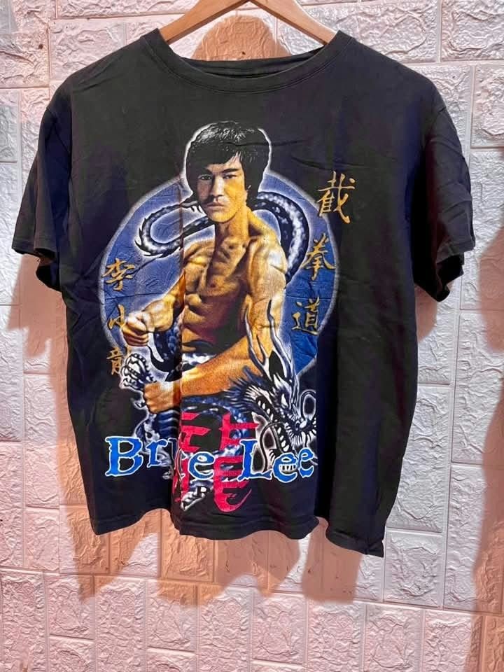 Bruce Lee Graphic Print Black T-Shirt (Category: Tshirts & Polo Shirts ) located in Manila. Submitted by carlosrexc26753 (Listing ID 1469826438, Image 1). Description: - Color: Black - Material: Comfortable cotton - Design: Large Bruce Lee graphic print on the front with dragon illustration and Chinese calligraphy - Branding: Bold blue Bruce Lee lettering near the hem - Fit: Relaxed fit with classic crew neck and short sleeves - Condition: Brand 