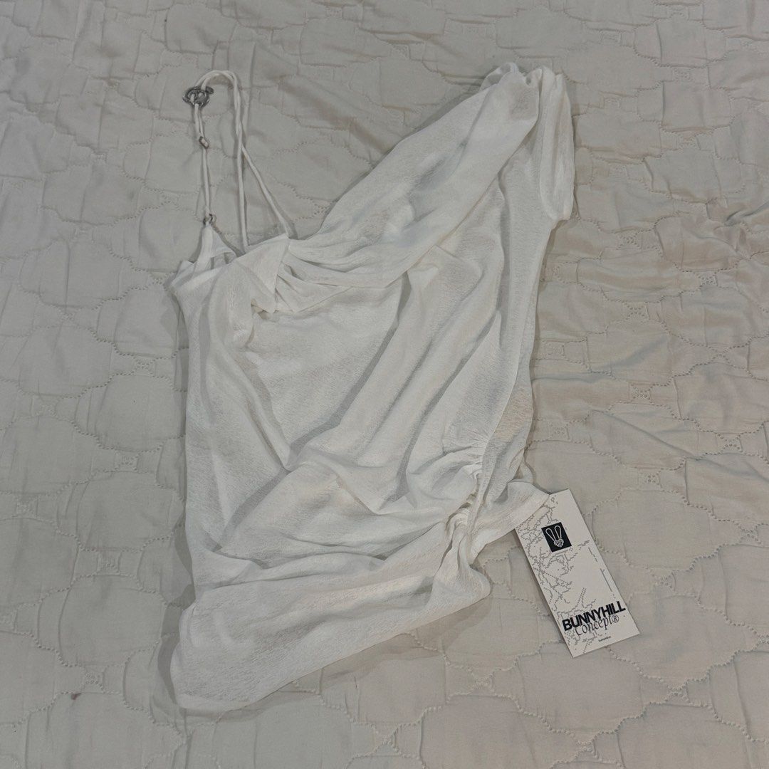 BunnyHill Concept White Samir Top (Category: Sleeveless) located in Manila. Submitted by williamest22 (Listing ID 1469925236, Image 2). Description: Price is Negotiable! - Size 2 (Medium) - Recommended Weight: 49-57 kg - Bust: Below 84 cm - Condition: Brand new with store tag attached - Color: White - Design: Asymmetrical neckline with unique strap details and gathered fabric down the side - Material: Soft and semi-sheer - Style: Chic, trendy, an