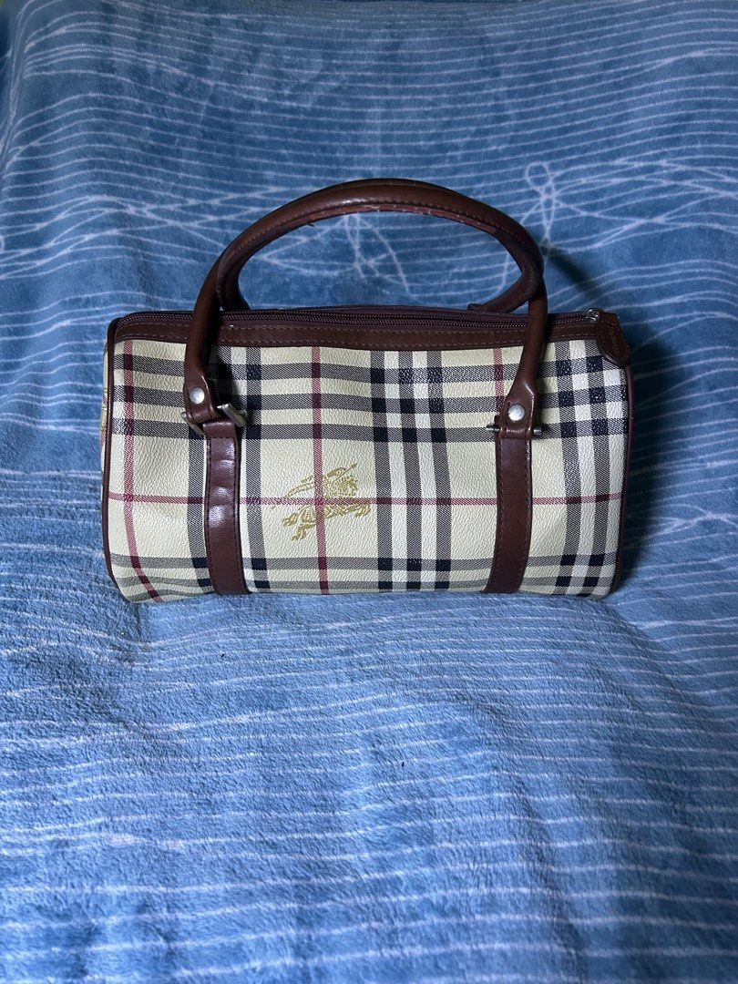 Burberrys Vintage Check Barrel Handbag (Category: Clutches) located in Quezon City. Submitted by thriftxgoods (Listing ID 1469896629, Image 2). Description: - Authentic vintage Burberrys barrel bag in iconic check print - Rich brown leather handles and trim with structured leather-paneled base - Secure top zip closure featuring an embossed leather pull tab - Signature gold equestrian knight logo on front patch and canvas - Clean interior lining e