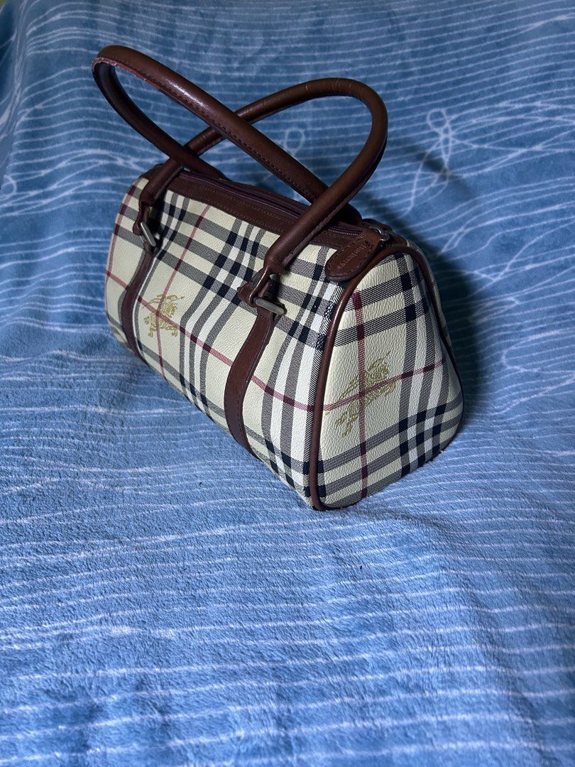 Burberrys Vintage Check Barrel Handbag (Category: Clutches) located in Quezon City. Submitted by thriftxgoods (Listing ID 1469896629, Image 3). Description: - Authentic vintage Burberrys barrel bag in iconic check print - Rich brown leather handles and trim with structured leather-paneled base - Secure top zip closure featuring an embossed leather pull tab - Signature gold equestrian knight logo on front patch and canvas - Clean interior lining e