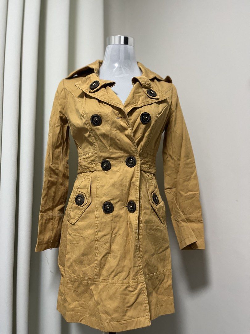 Camel Trench Coat Double Breasted (Category: Coats, Jackets and Outerwear) located in Angeles City. Submitted by pinkpool (Listing ID 1469765797, Image 1). Description: - Style: Classic camel trench coat - Closure: Double-breasted front with dark brown buttons - Details: Lapel collar, long sleeves, two front pockets, structured waistline with belt loops - Material: Lightweight cotton blend, ideal for layering - Fit: Standard fit - Condition: Read