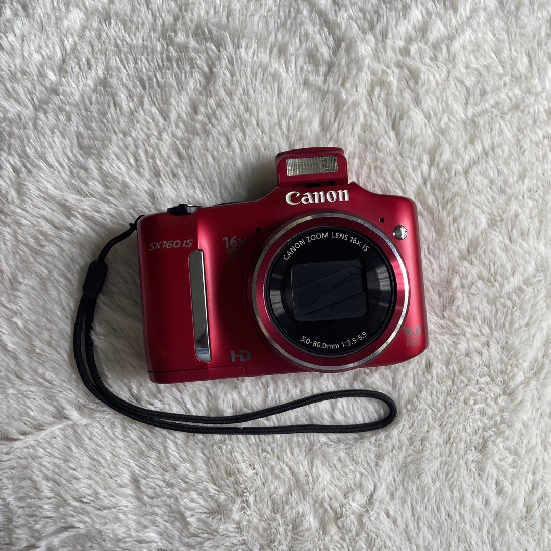 Canon PowerShot SX160 IS Red Digital Camera (Category: Cameras) located in Iloilo. Submitted by sesamhie_ (Listing ID 1469823041, Image 2). Description: - Model: Canon PowerShot SX160 IS (Vibrant Red) - Resolution & Zoom: 16.0 megapixels with 16x optical zoom - Power: Uses standard AA batteries - Included Bundle: 2 x Amazon Basics rechargeable AA batteries and a SanDisk Ultra 16GB SD card - Body: 9/10 (good condition, no visible major scratches) 